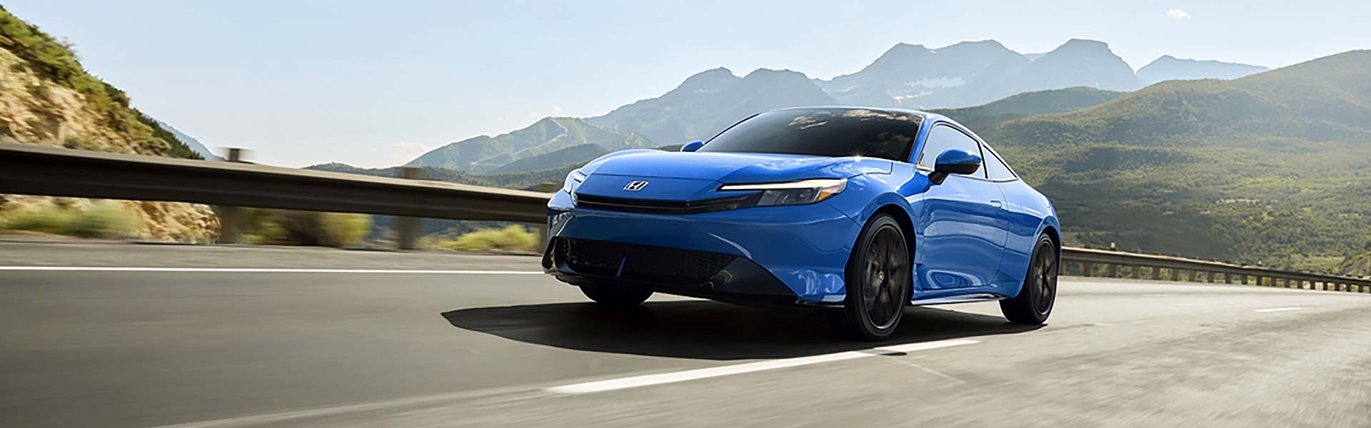 Honda Prelude Hybrid riding in a road surrounded by mountains.