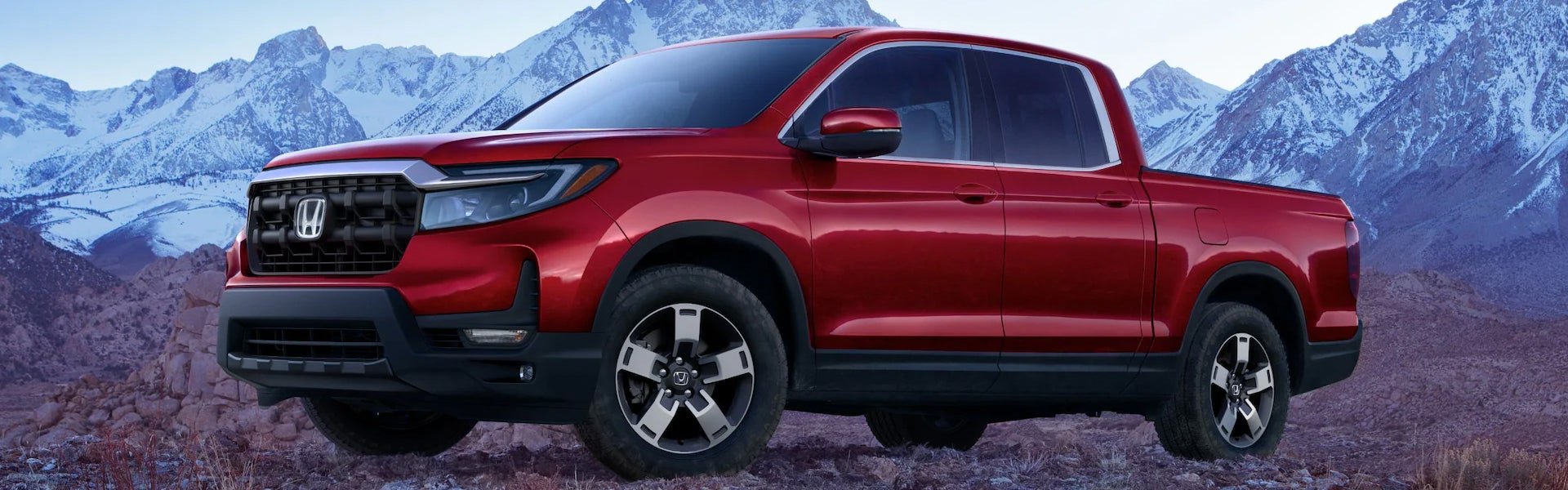 Red color 2026 Honda Ridgeline showcasing its unique design and surrounded by mountains.